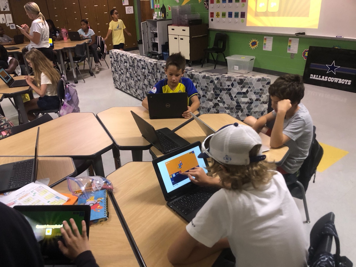 Students at shared tables playing CodeAlgo on Chromebooks